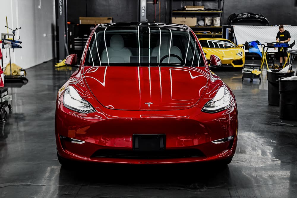 Röd Tesla under LED-belysning i en modern verkstad (illustrationsbild)
